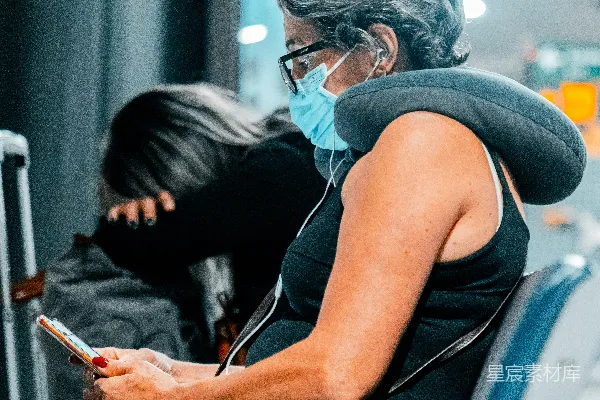 高清摄影 蓝色T恤的女人戴着白色的耳机，手持智能手机。