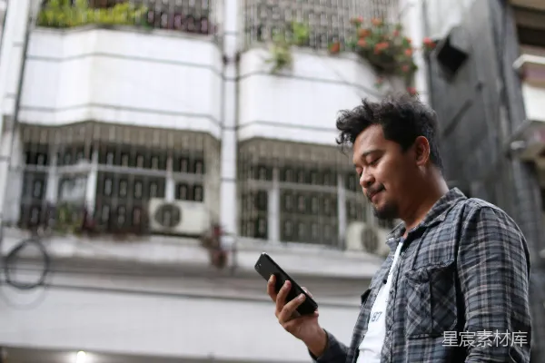 高清摄影 蓝白格衬衫穿着的男人手持黑色智能手机