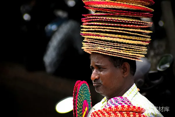 高清摄影 一个男子手持扇子并戴着一顶色彩鲜艳的帽子。