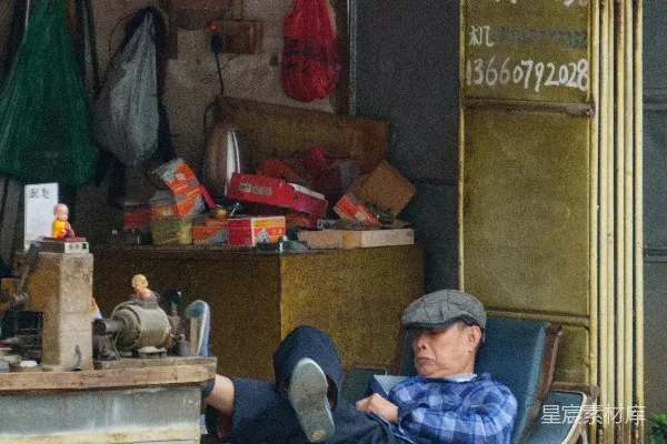 高清摄影 一个男人坐在椅子前，面前是一家店铺。