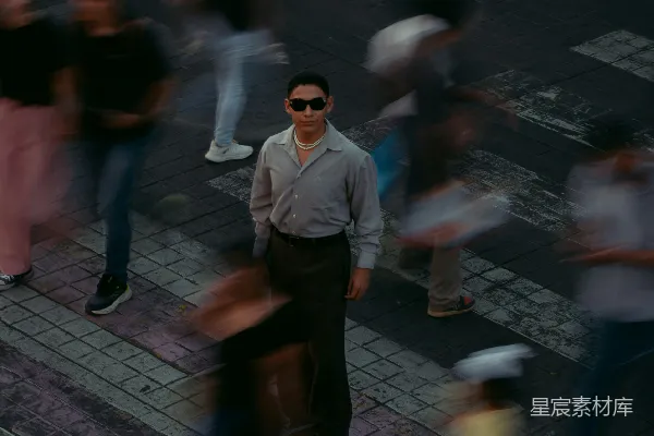 高清摄影 戴着墨镜的人站在十字路口静止不动，周围是模糊的人群。