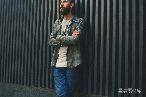 高清摄影 身穿蓝 denim 裤子的男人站在黑色墙旁