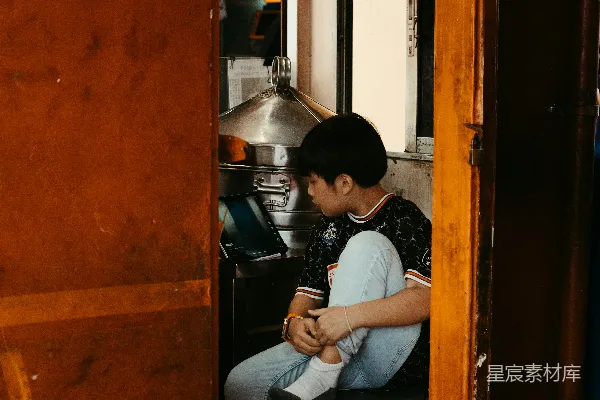 高清摄影 一个男孩坐在一个小摊子里。