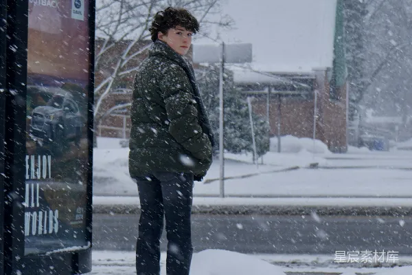 高清摄影 站在雪中的一个人，旁边是公交站。