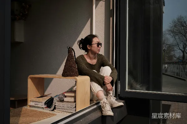 高清摄影 一个女人坐在窗台上望向窗外。