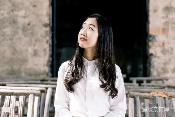 高清摄影 白衬衫连衣裙上衣、白裤的女人，穿着苹果站在椅子上，手扶苹果。