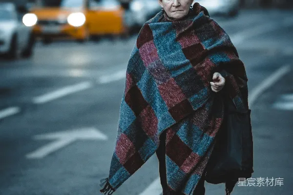 高清摄影 一个女人正在街上带着毯子走着。