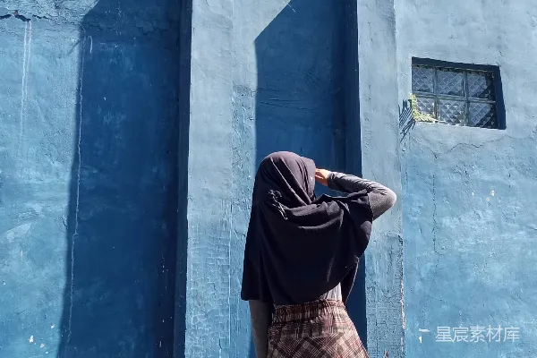 高清摄影 一个女人站在一栋蓝色建筑前