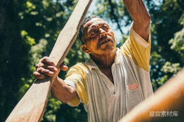 高清摄影 灰色圆领T恤的男人手持着一根棕色的木棍