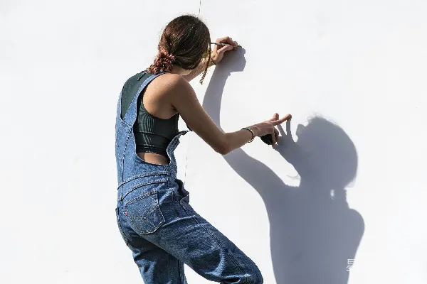 高清摄影 身穿蓝 denim 牛仔裤和黑色紧身 T 恤的女人坐在椅子上。