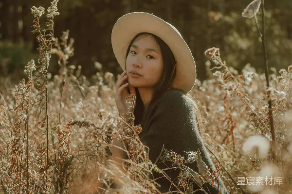 高清摄影 黑色长袖上衣的女人戴着浅褐色的太阳帽站在褐色的草地上。