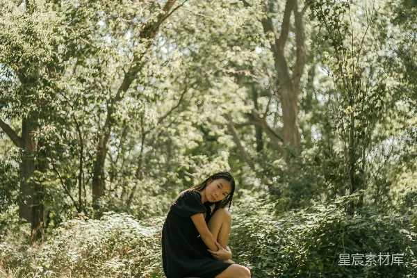 高清摄影 黑色上衣的女人坐在棕色木椅上，下面是一片绿色的树林，在白天。