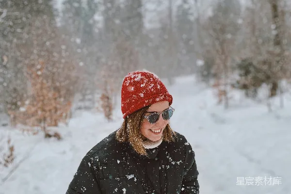 高清摄影 一个女人站在雪地里，戴着一顶红色的帽子。