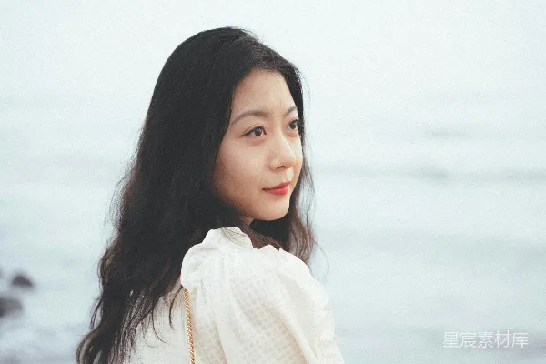 高清摄影 海滩上站着一位妇女，旁边是海洋。