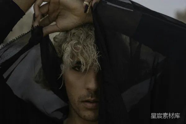 高清摄影 一个 blonde头发的男人正在拿着黑色夹克。