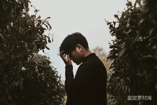 高清摄影 黑色西装男子站在绿植旁的白天
