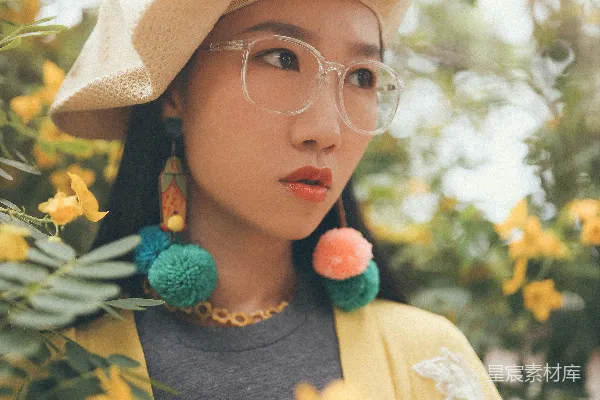 高清摄影 聚焦于侧脸凝视左侧的女人的照片，周围环绕着黄色花瓣的花朵。
