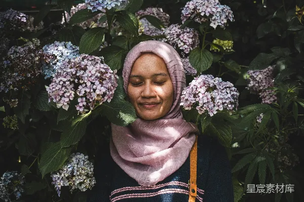 高清摄影 身穿黑白色 floral 穹顶状头巾的女人站在绿色植物旁