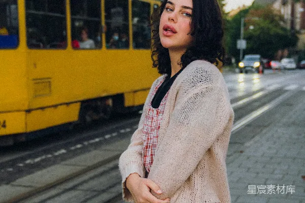 高清摄影 一个女人站在一辆黄色火车旁边的人行道上