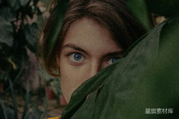 高清摄影 一个蓝眼睛的女人躲在绿色的植物后面