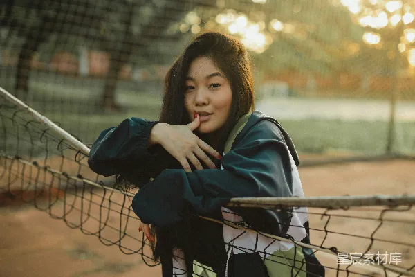 高清摄影 身穿蓝色和白色夹克的女人坐在黑色金属椅上，白天场景。