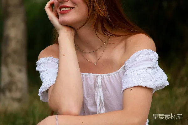 高清摄影 一个穿着白色裙子的女人坐在草地上。
