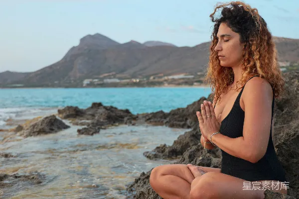 高清摄影 黑色上衣的女人坐在海边岩石上，白天的景象