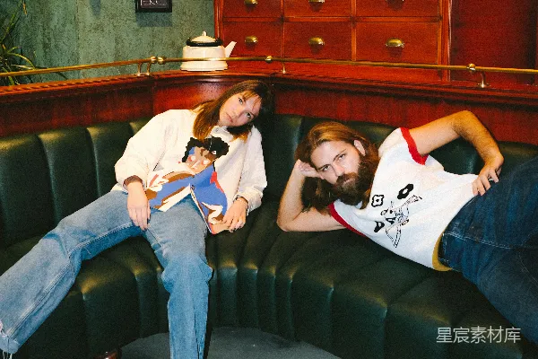 高清摄影 白色上衣和蓝色牛仔裤的女人坐在黑色皮质沙发上。