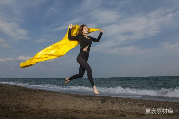高清摄影 黄色上衣和黑色紧袜的女人在海滩上白天拿着黄色的纺织品