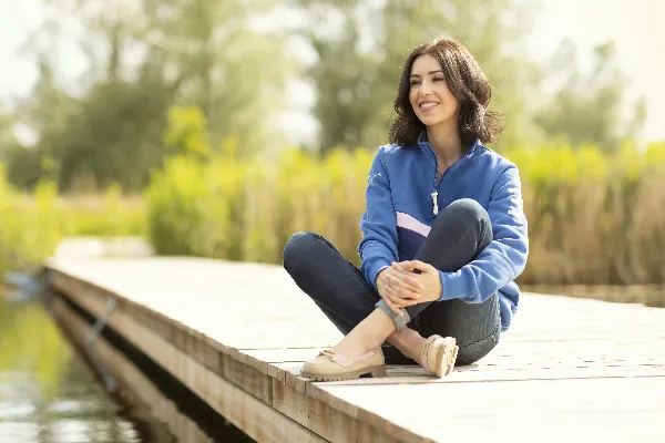 高清摄影 一位妇女正坐在岸边的码头上。