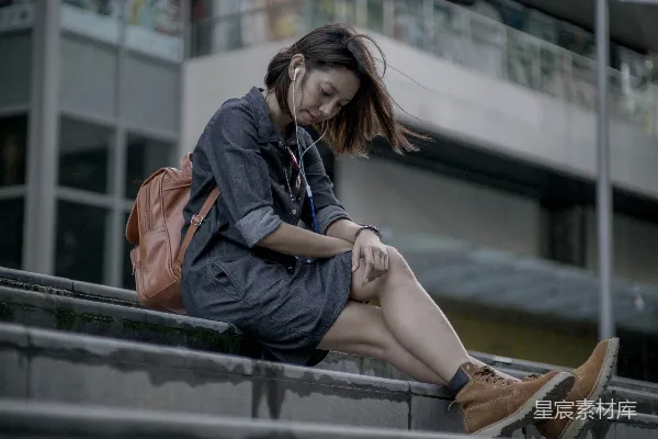 高清摄影 一个女人坐在 ledge 上使用她的手机。