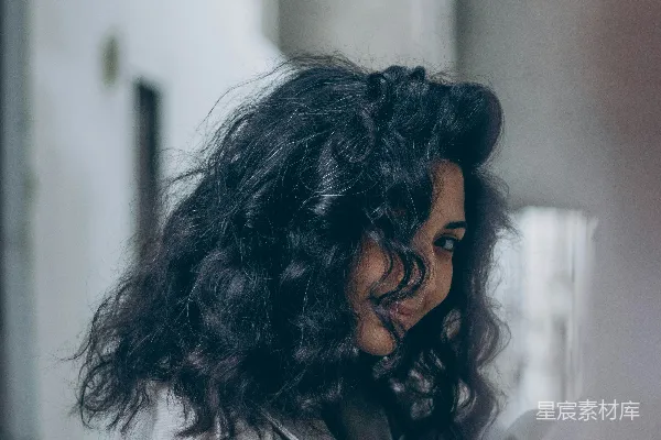 高清摄影 一个留有 curly hair 的女性正在看着她的手机。