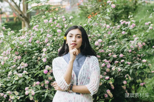 高清摄影 白灰条纹连衣裙的女人站在一旁的粉色花朵旁