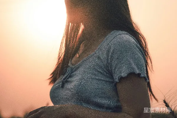 高清摄影 夕阳下，一位女子坐在麦田里。