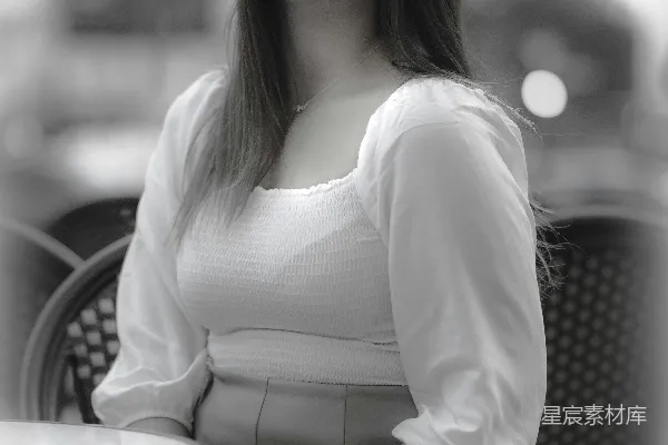 高清摄影 一位穿着白色连衣裙的女子坐在一张桌子旁。