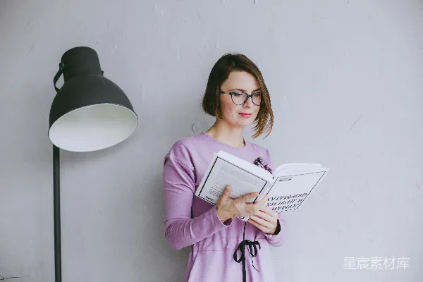 高清摄影 一个女人站在灯旁边读书。