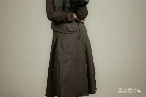 高清摄影 一个穿着棕色衣服的女人拿着一个黑色手袋