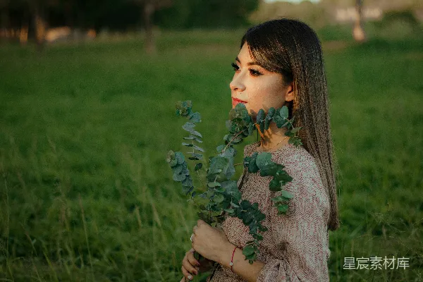 高清摄影 一个妇女站在田里拿着一株植物