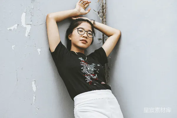 高清摄影 一个女人靠在墙上，双手放在头上