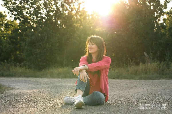 高清摄影 女人在阳光下的路旁坐着微笑。