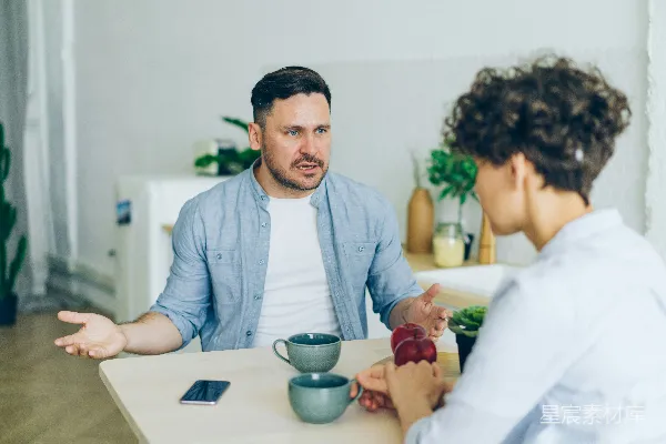 高清摄影 一个男人坐在一张桌子旁与一个女人交谈。
