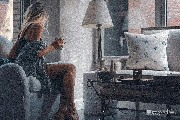 高清摄影 坐在灰色沙发椅上的女人拿着一个杯子。