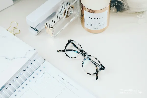 高清摄影 黑色边框的眼镜旁边是一本螺旋式笔记本。