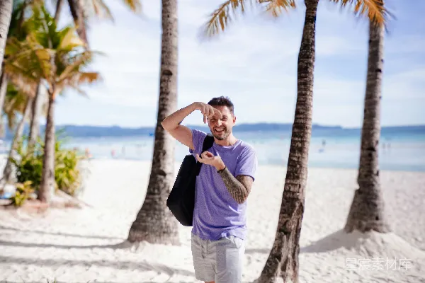 高清摄影 一个男人站在沙滩上，旁边是 palm trees。