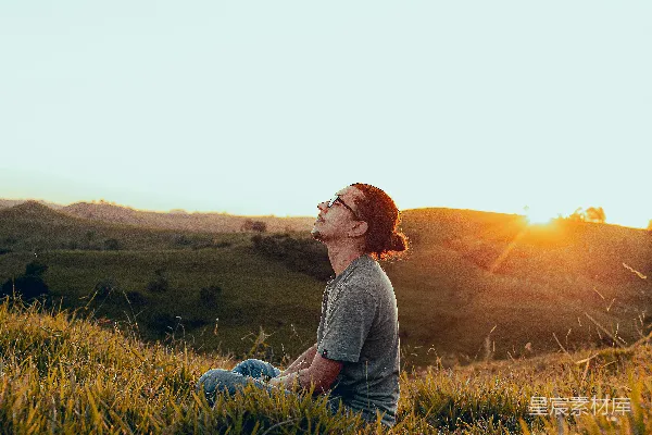 高清摄影 白衬衫男士坐在绿色草地上的傍晚景象