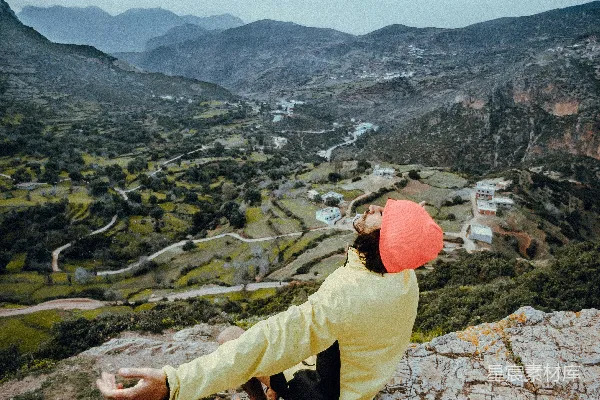 高清摄影 穿着黄色夹克和棕色长裤的男人在岩石山丘上白天坐着