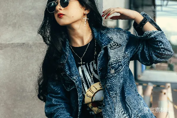 高清摄影 一个女人坐在墙上，穿着牛仔夹克。