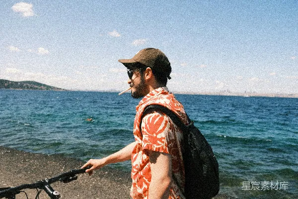 高清摄影 海边一名骑自行车背着背包的人。
