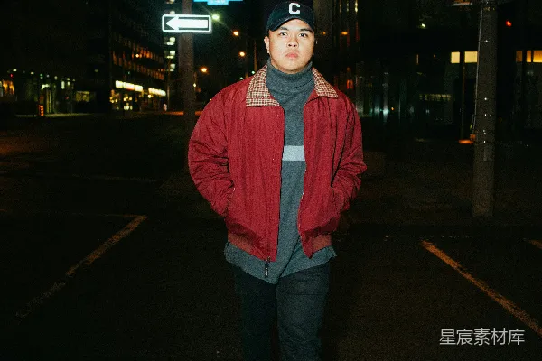 高清摄影 红衣男子站在 sidewalk 上，夜间的景象。