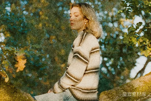 高清摄影 一个女人坐在树干上，眼睛闭着。